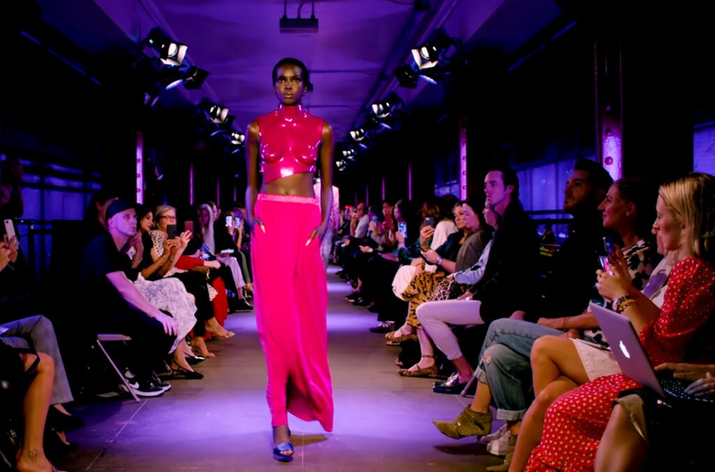 Tom Ford Spring Summer 2020. Electric Pink outfit by Tom Ford featuring a lacquered acrylic anatomical breastplate, womenswear.