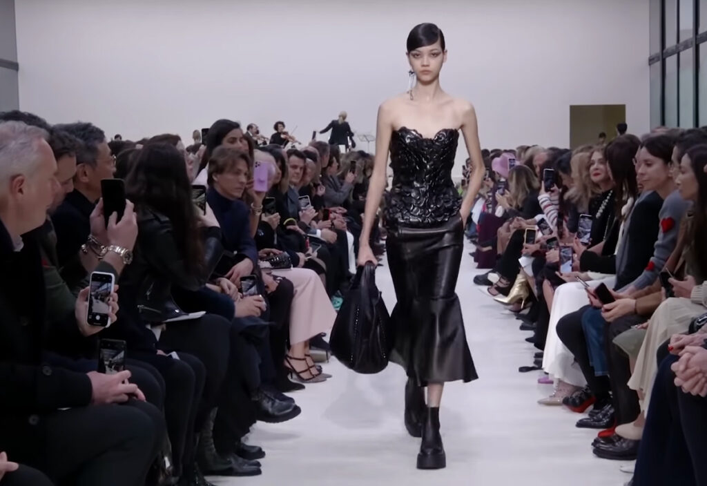 Evening wear alluring black leather top and black skirt look with a black bag. A Symphony of Fashion with The Fall Winter 2020 Collection by Valentino